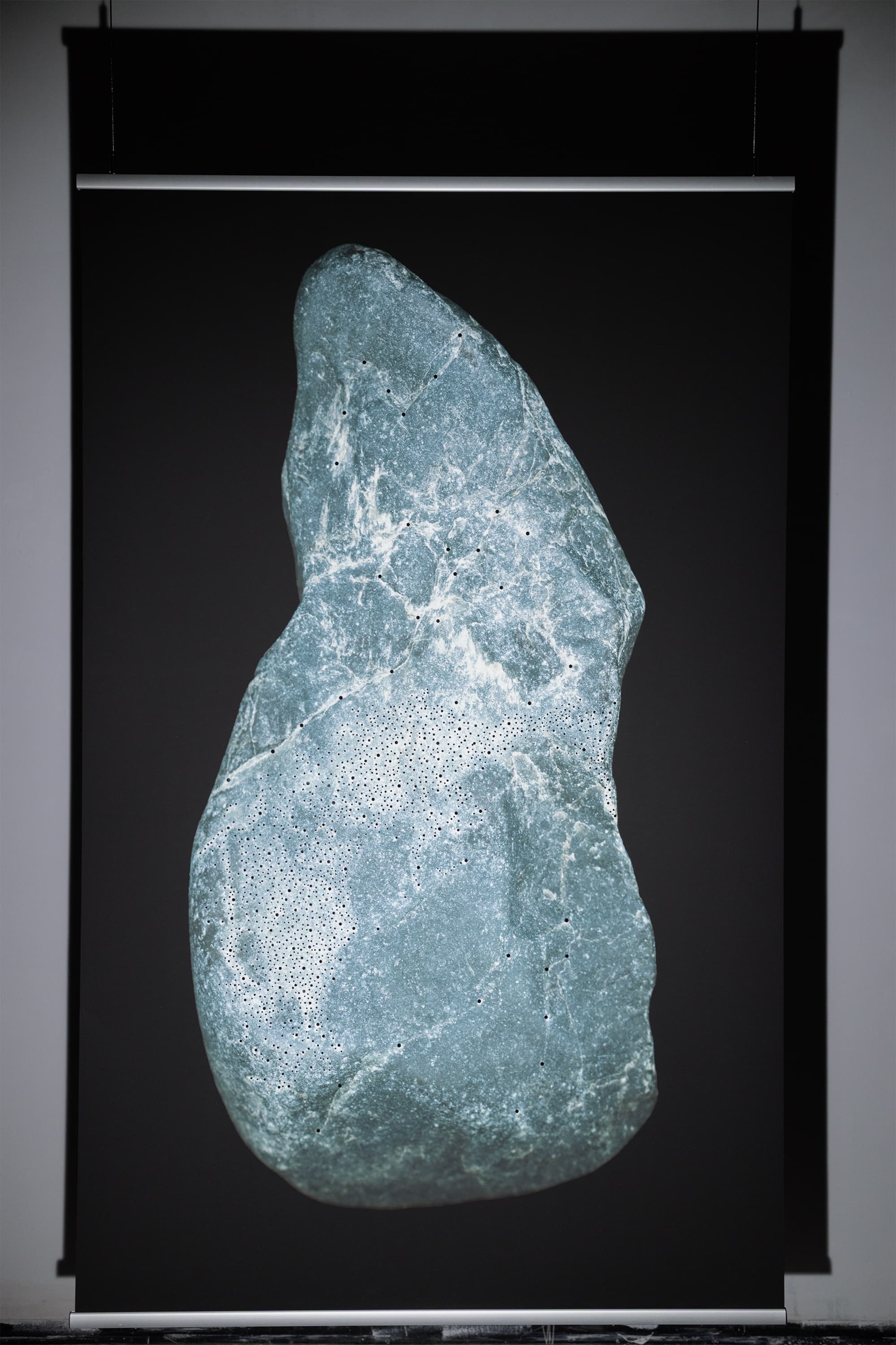The image is a high-resolution digital scan of the surface of a stone collected along the Dora River in Turin, Italy. Printed at a large scale, it amplifies the visual experience of the traces emerging from the rock. These figures are considered acheiropoietic images—forms not made by human hands. The research draws on the practice of reading stones as a form of divination. The images revealed on the rock’s surface guide the divinatory act, activating the imagination and perceptual sensitivity of the seer.